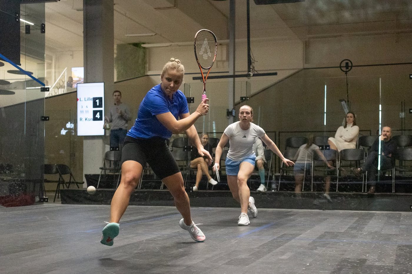 Women's match in progress with spectators watching